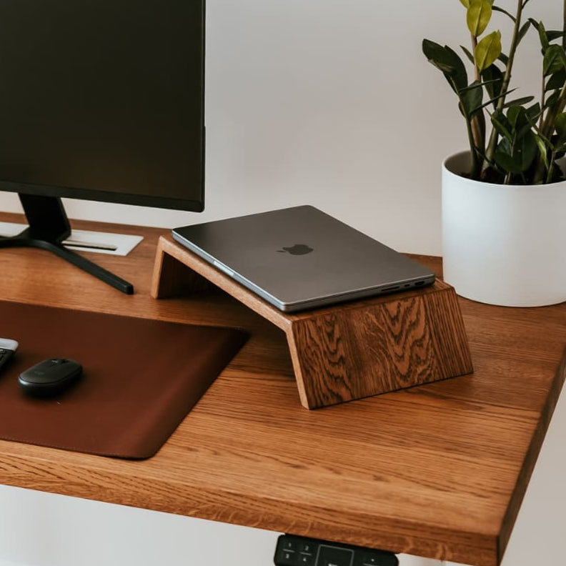Wooden desk with computer setup, including a monitor, laptop, keyboard, and plant.